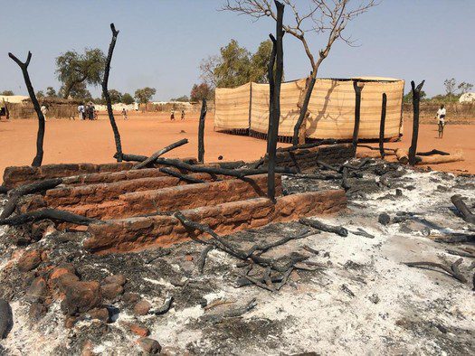 Charred remains of the church, and temporary meeting tent in background.