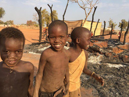 Refugee children play in the smoldering remains. 